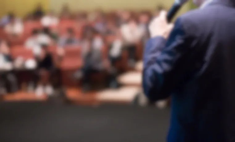 Blurred photo of speaker with audience