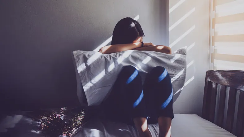 Woman holding pillow in dark room